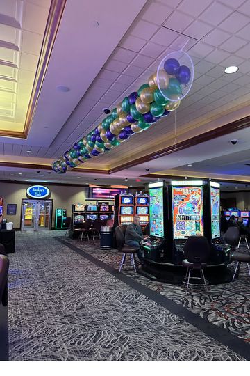 Casino interior with slot machines and ceiling balloon decoration.
