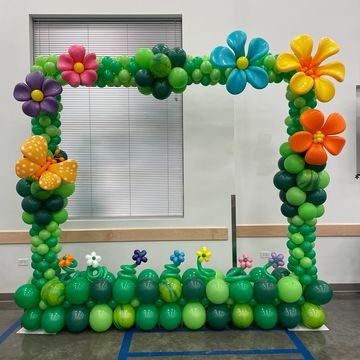 Colorful balloon frame decorated with green balloons and flower shapes.