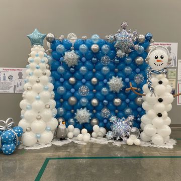 Festive winter scene with balloon snowman, tree, and gift.