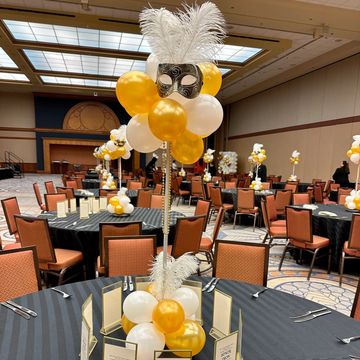 Elegant banquet tables decorated with gold and white balloons and feathers.