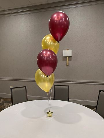 Red and gold balloons on a round table with chairs.