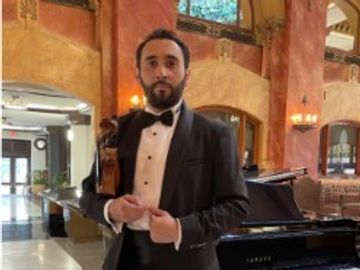 Man in tuxedo holding a violin.