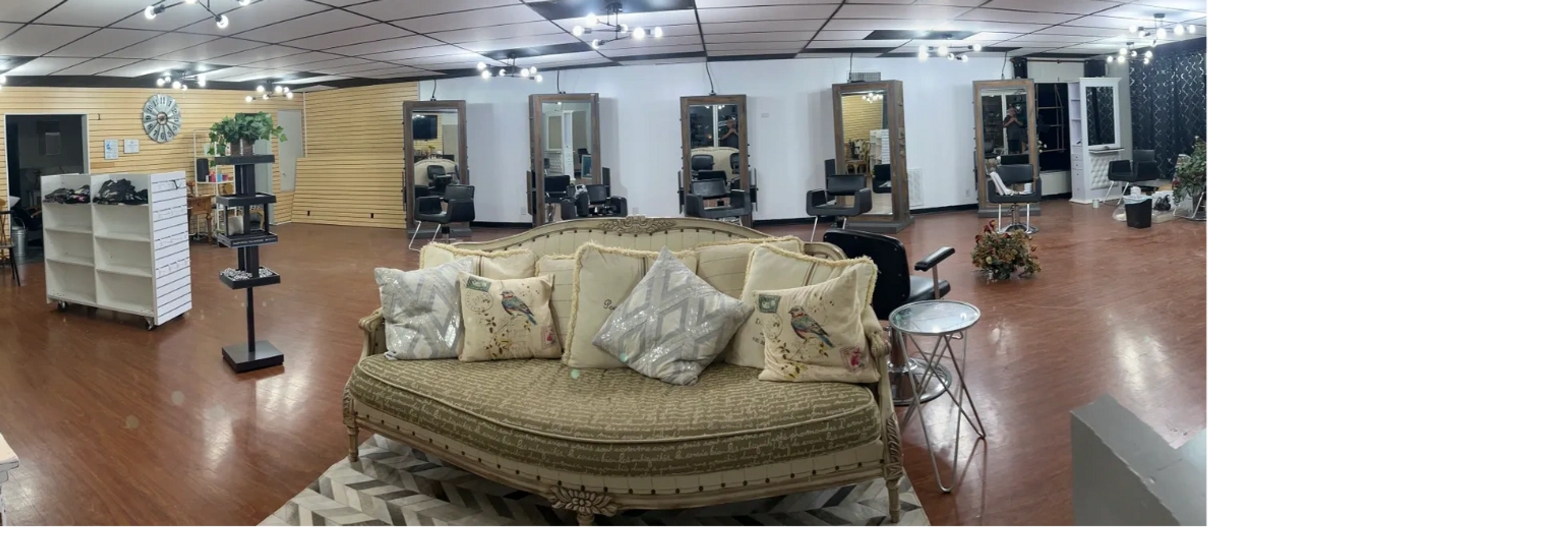Spacious, well-lit hair salon with vintage sofa and multiple styling stations.