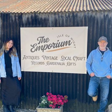 Two people stand beside a sign for The Emporium on Isle of Wight.