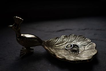 Metal peacock tray holding a ring.
