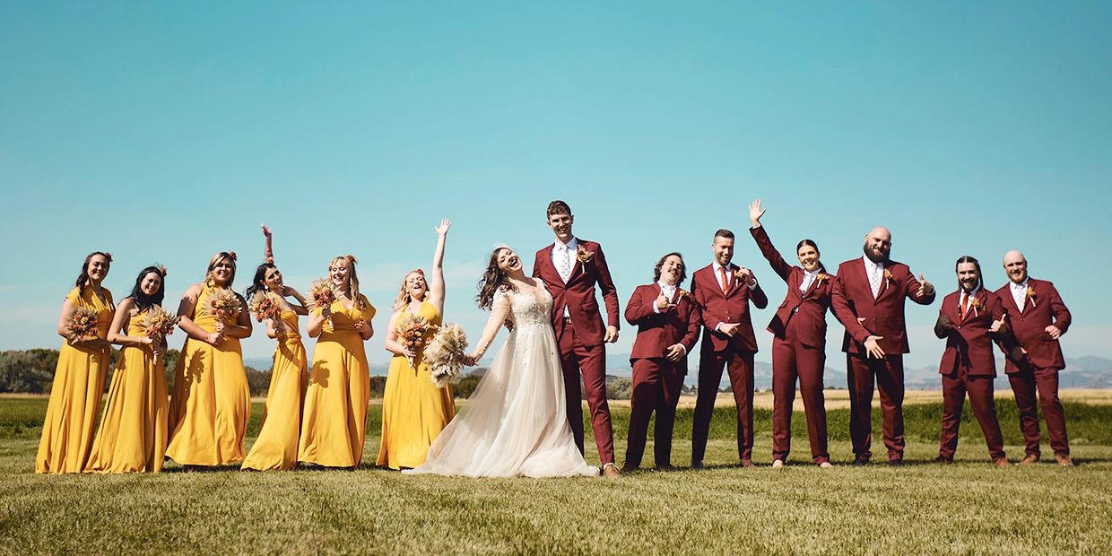 Wedding party with bride in white, bridesmaids in yellow, and groomsmen in maroon suits.
