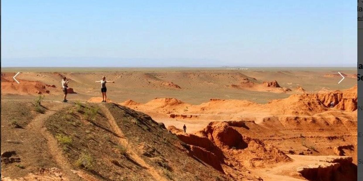 Two people enjoying a sunny day on rocky, desert terrain with clear blue sky.