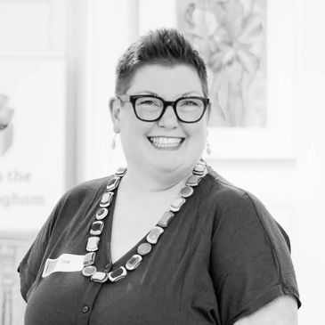 Smiling person wearing glasses and a chain of office in a black and white photo.
