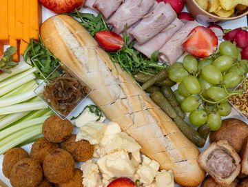 Ploughman's picnic platter with a selection of cheeses, crusty bread, pickles, cold cuts, pork pie