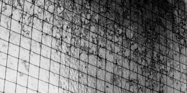 Close-up of a textured, grid-patterned surface with dark stains.