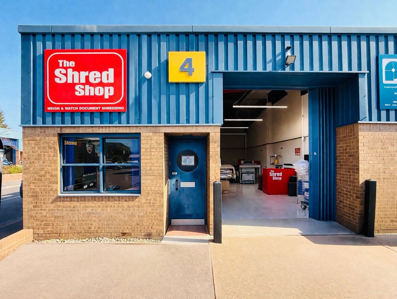 Exterior of The Shred Shop with a blue and brick facade and open garage door.