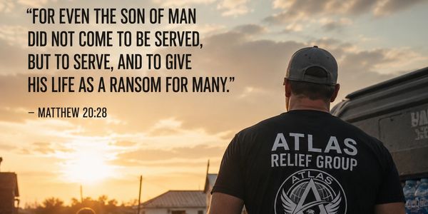 A man wearing an ATLAS Relief Group shirt gazes at a sunset with a Bible verse.