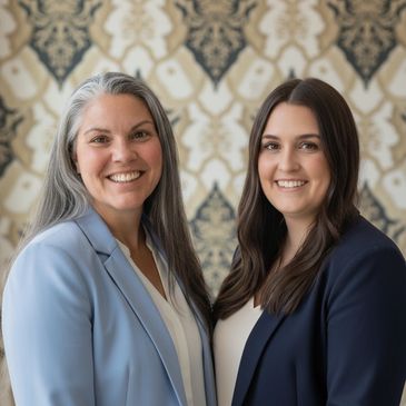 Two professional women smiling, dressed in business attire with a patterned background.