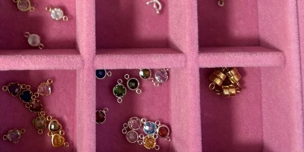 Small colorful jewelry charms in pink organizer.
