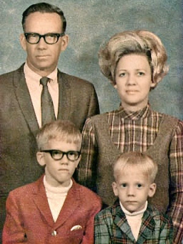Vintage family portrait with parents and two boys in formal attire.