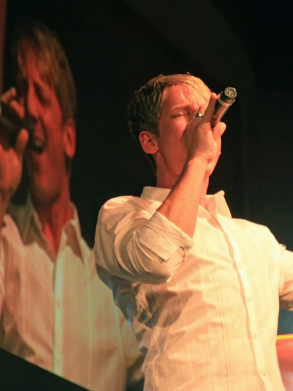 Male singer passionately performing on stage with microphone.