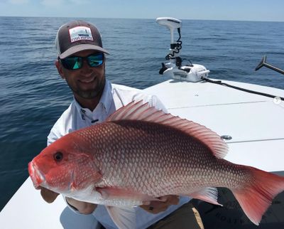 Capy Kyle holding a red snapper he caught on a near shore fishing charter off panama city beach and 