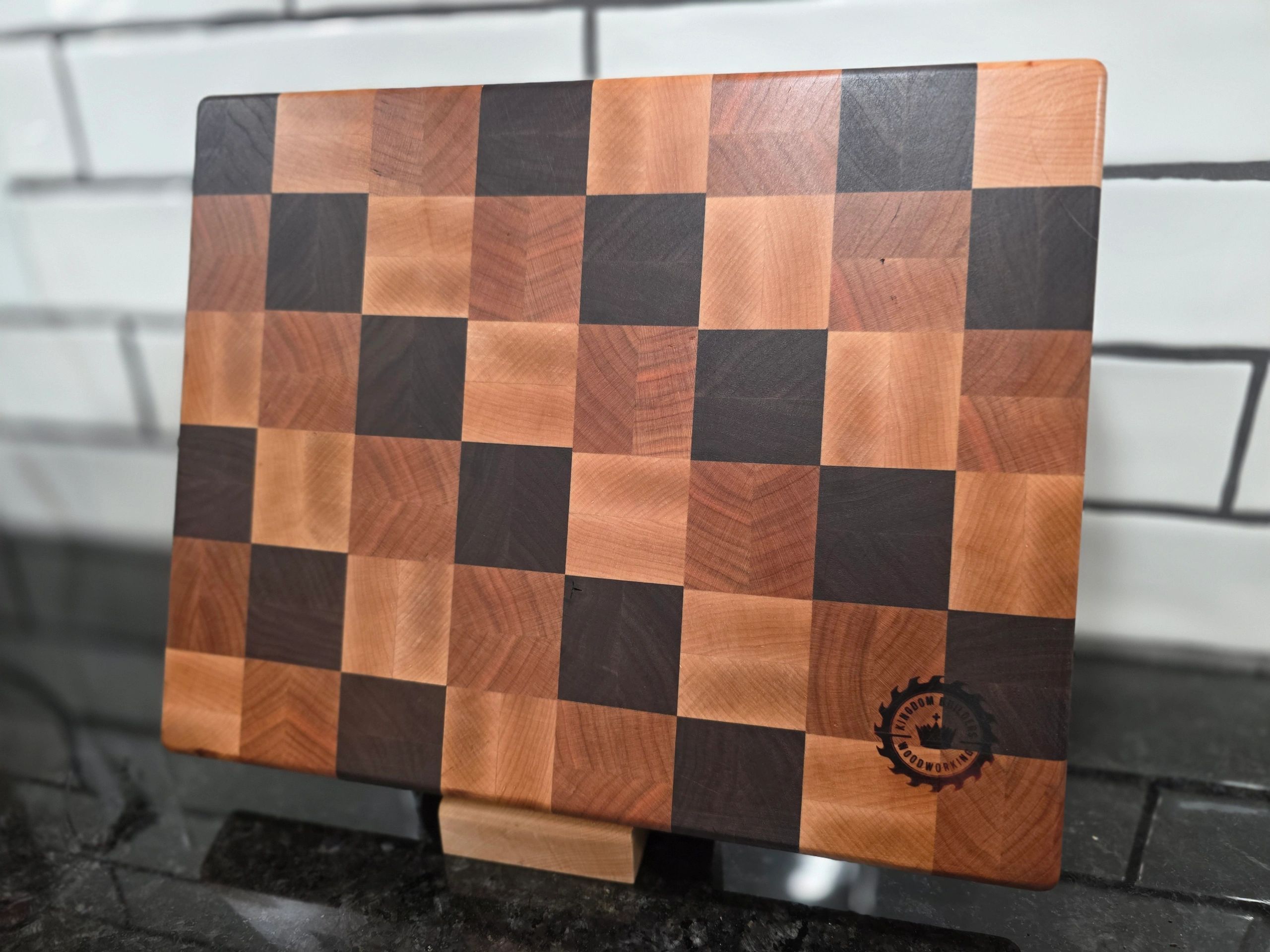 Checkerboard wooden cutting board with contrasting wood tones.