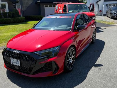 Red Audi car parked on street in daylight.