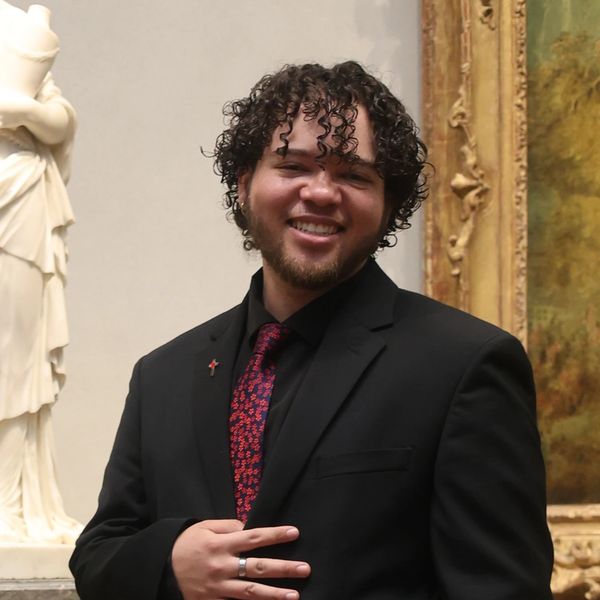 Administrative Director Tyrick McLeish, standing next to a statue of the Virgin Mary & Christ.