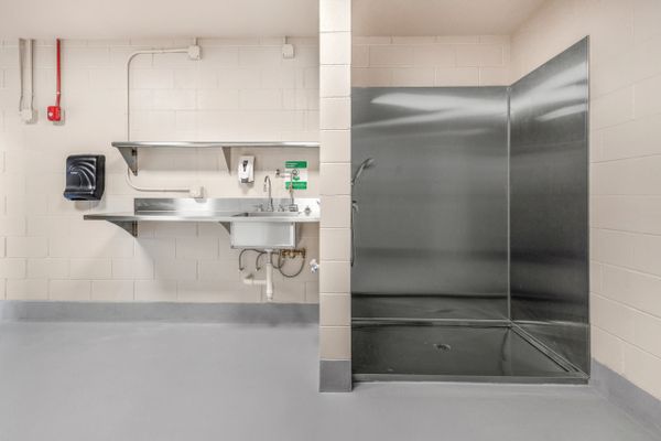 Clean, industrial-style handwashing and shower area with stainless steel fixtures.