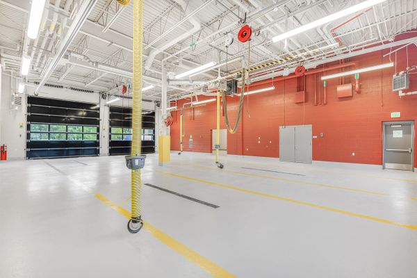 Empty, clean fire station garage with yellow exhaust hoses and red brick walls.