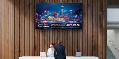 Corporate office reception with digital signage displaying welcome message.