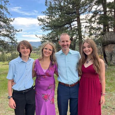 Family smiling outdoors in formal attire.