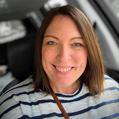 Smiling woman with shoulder-length brown hair in a striped sweater.