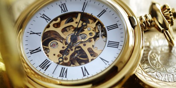 Close-up of a gold pocket watch with visible gears and Roman numerals.