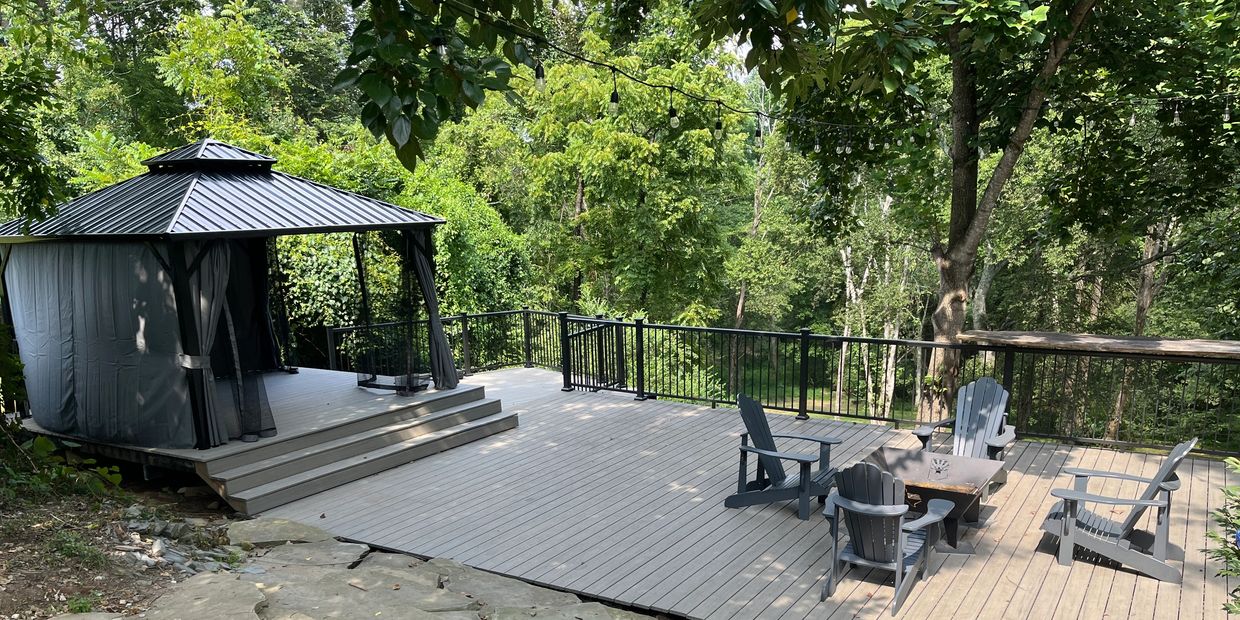 Large composite deck with metal hand railing and gazebo.  Adirondack chairs around a firepit