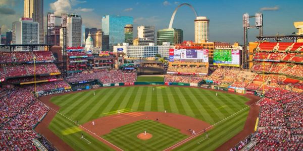 A baseball game at a stadium with city skyline and Gateway Arch.