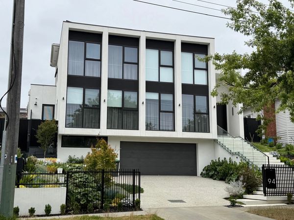 Modern white house with large windows and a black garage door.