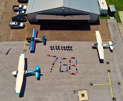 Aerial view of people and three small planes on an airstrip forming a design.