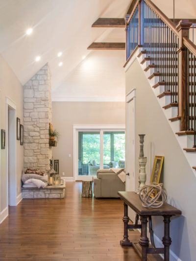 Bright hallway with staircase and stone fireplace.