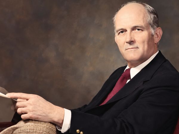 Mature man in suit sitting and holding papers.