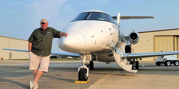 Man standing next to a private jet on the tarmac.