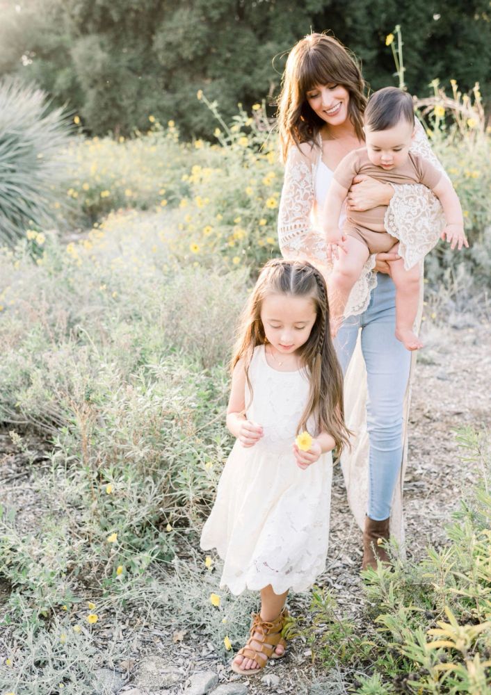 Mother and children in a sunny meadow with yellow flowers.