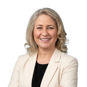 Smiling professional woman with blonde hair in a cream blazer and black top.