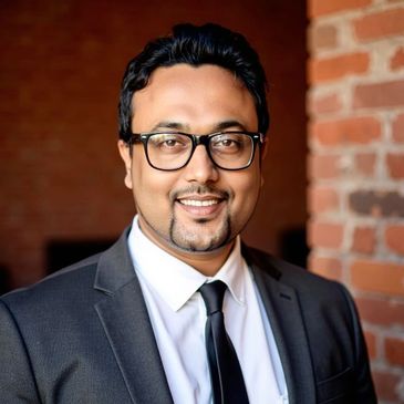 A smiling man in a black suit and glasses.