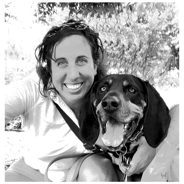 Woman smiling with her happy dog outdoors.