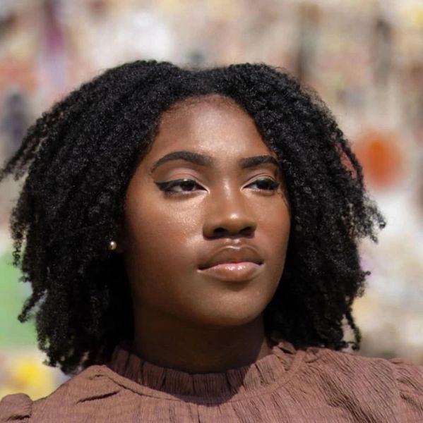 Confident young woman with natural curly hair and glowing skin.