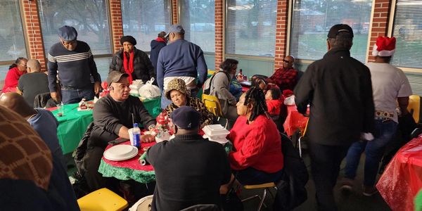 Large group of people dressed in holiday clothes sat at holiday decorated tables 