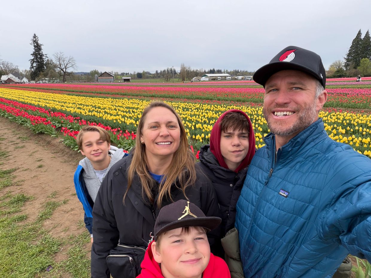 A smiling family poses in front of vibrant tulip fields outdoors.