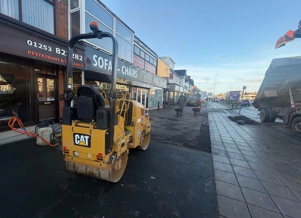 Road construction with machinery and workers on a sunny day.