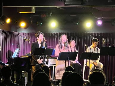 A group of four musicians performing on stage with microphones and music stands.