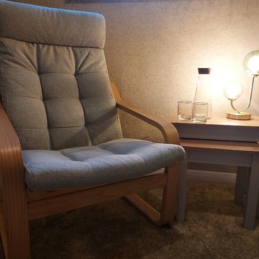 View of a comfortable hypnotherapy chair  in a safe, cosy room with soft lighting. 