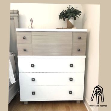 A stylish two-tone wooden dresser with decorative items on top.