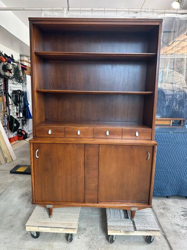 Mid-century wooden hutch with shelves, drawers, and sliding doors.