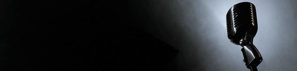 Vintage microphone illuminated by a spotlight on a dark stage.